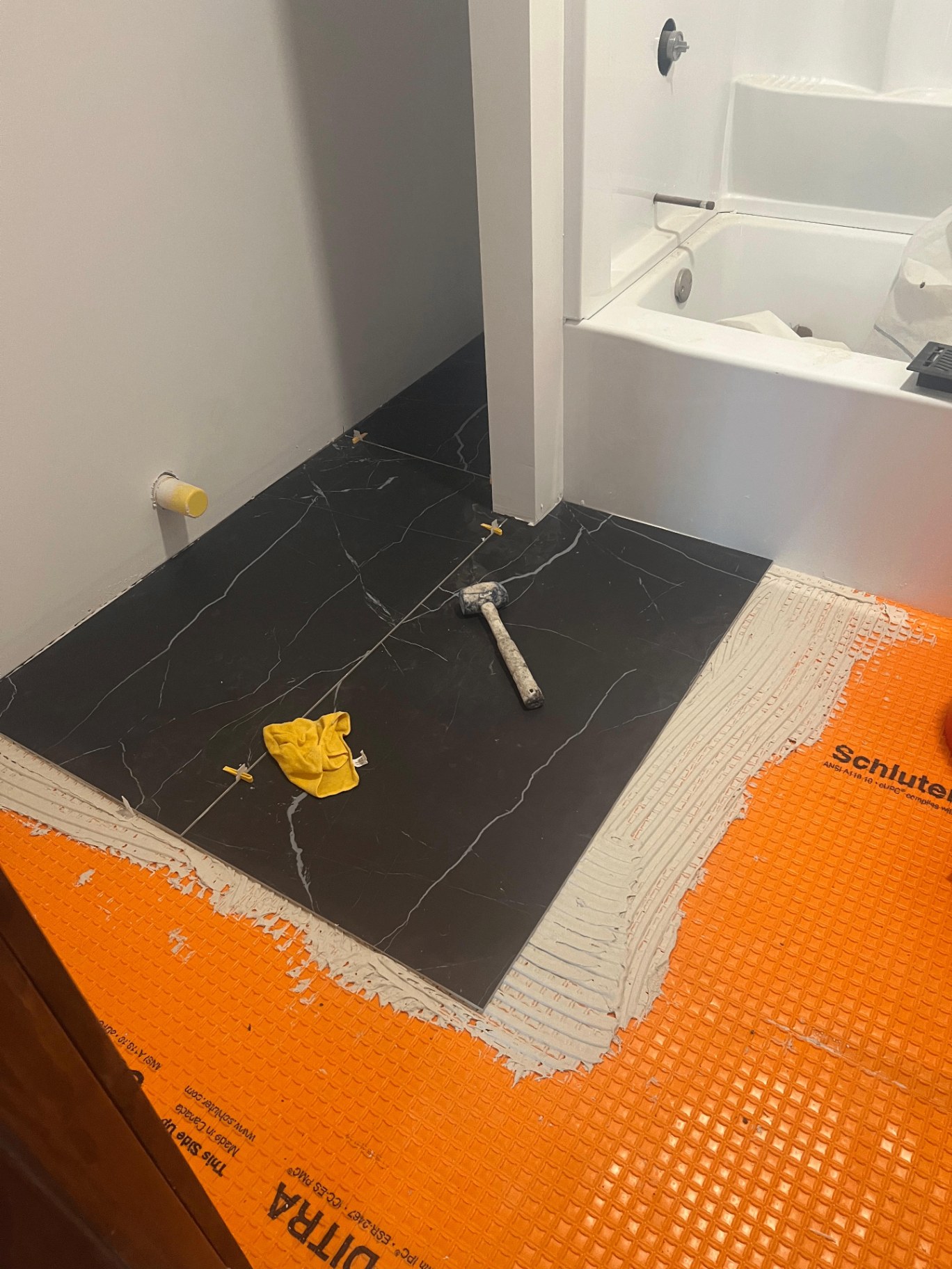 Bathroom floor tile installation in progress with spacers and thinset