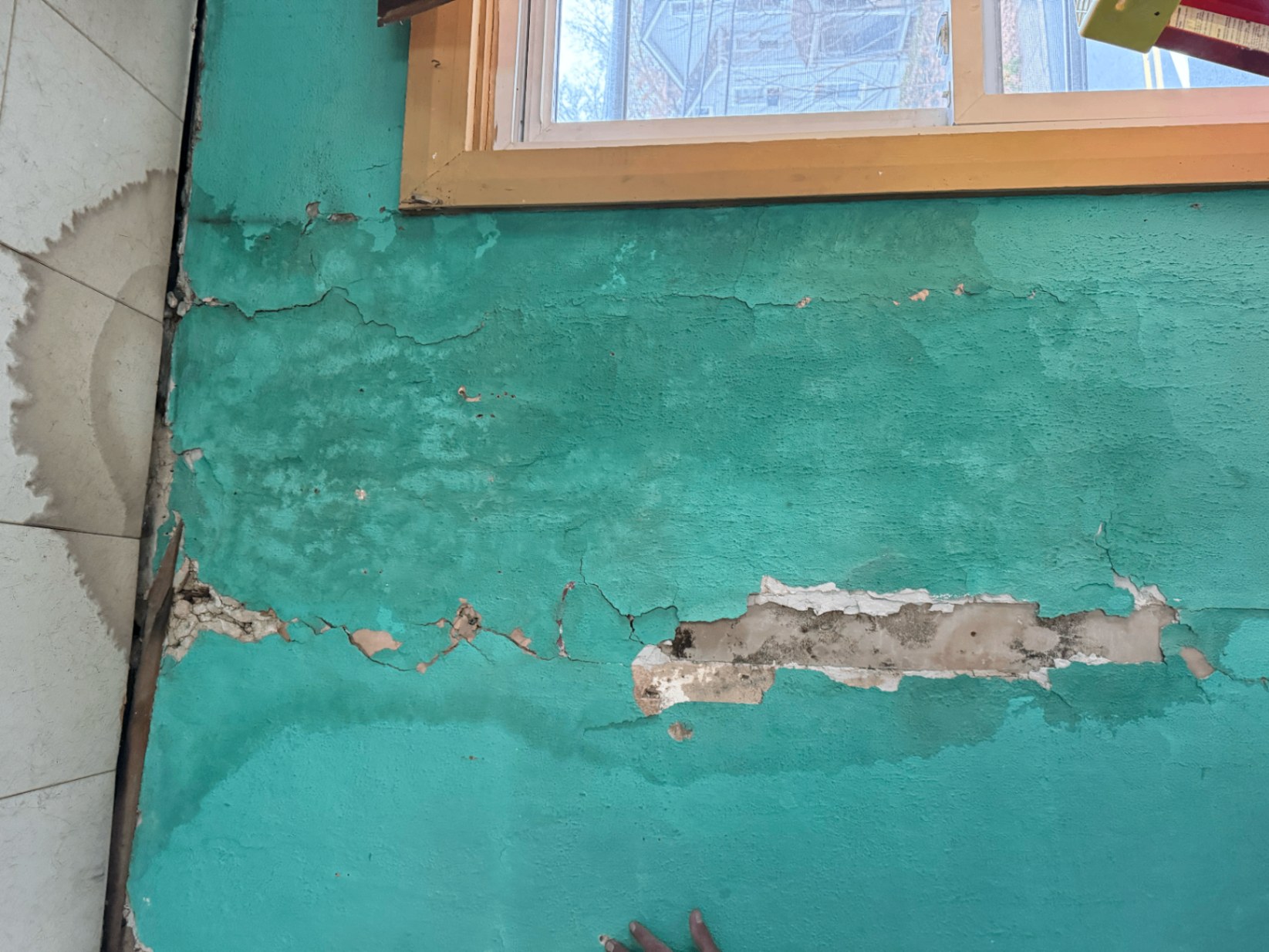 Damaged interior plaster wall under a window opened up during renovation prep and repair work
