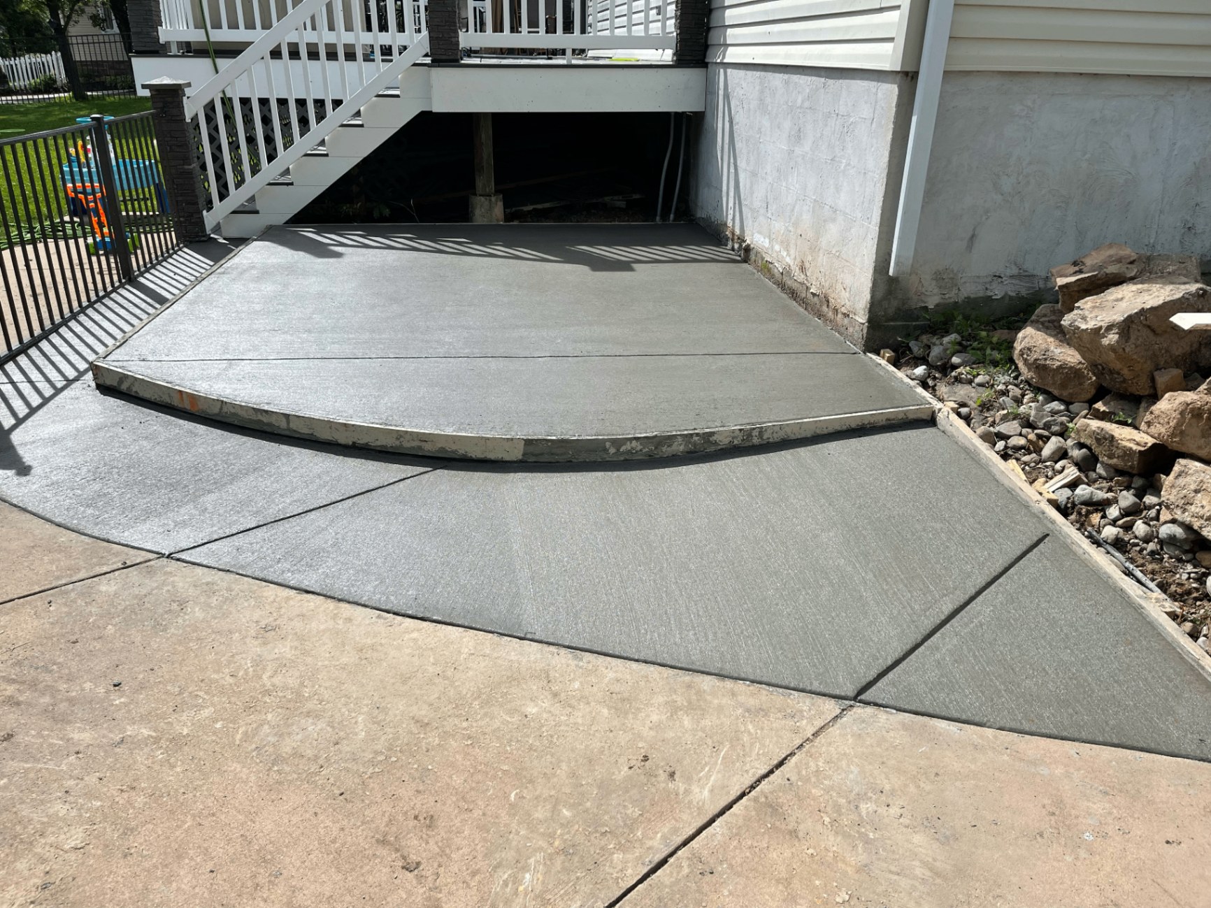 Broom-finished concrete patio pad and walkway under a residential deck