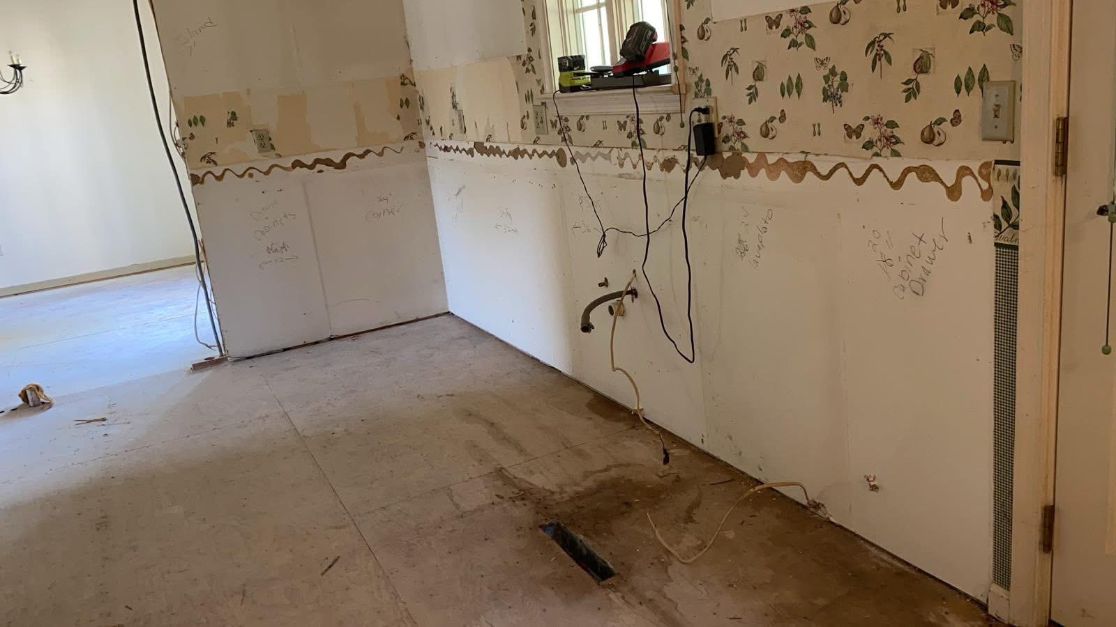 Kitchen mid-demolition — wallpaper stripped and cabinets removed