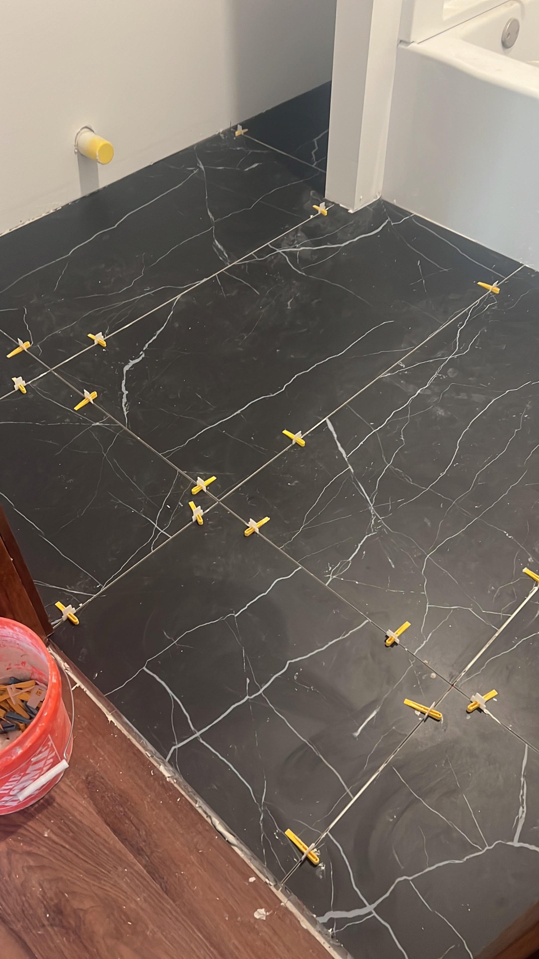 Close-up of bathroom floor tile layout with black marble-look porcelain and tight grout joints