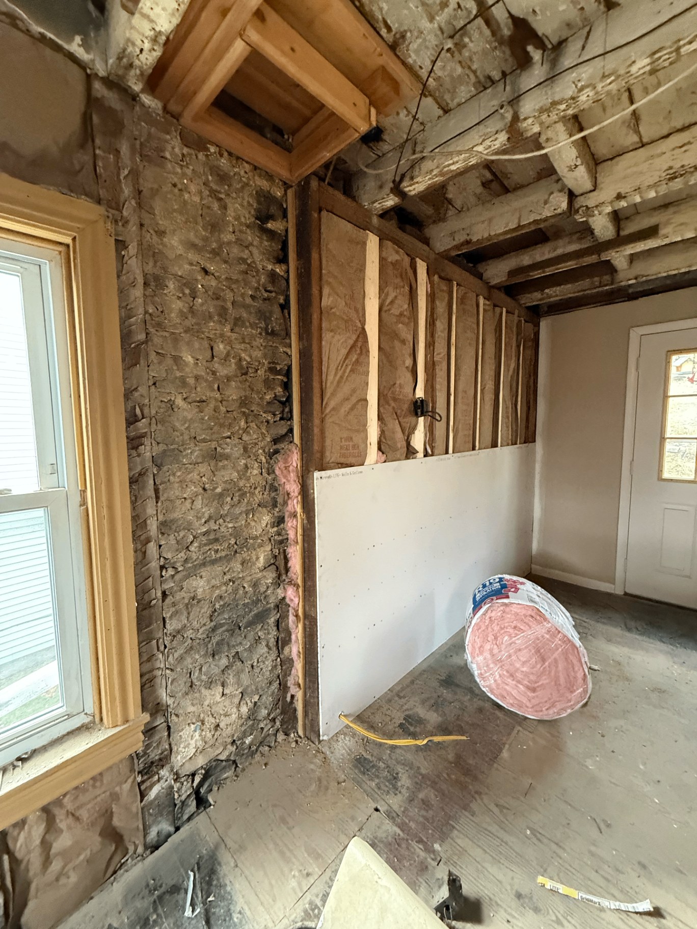 Bathroom subfloor demo — joists exposed and new plywood subfloor patched in during a full bathroom remodel